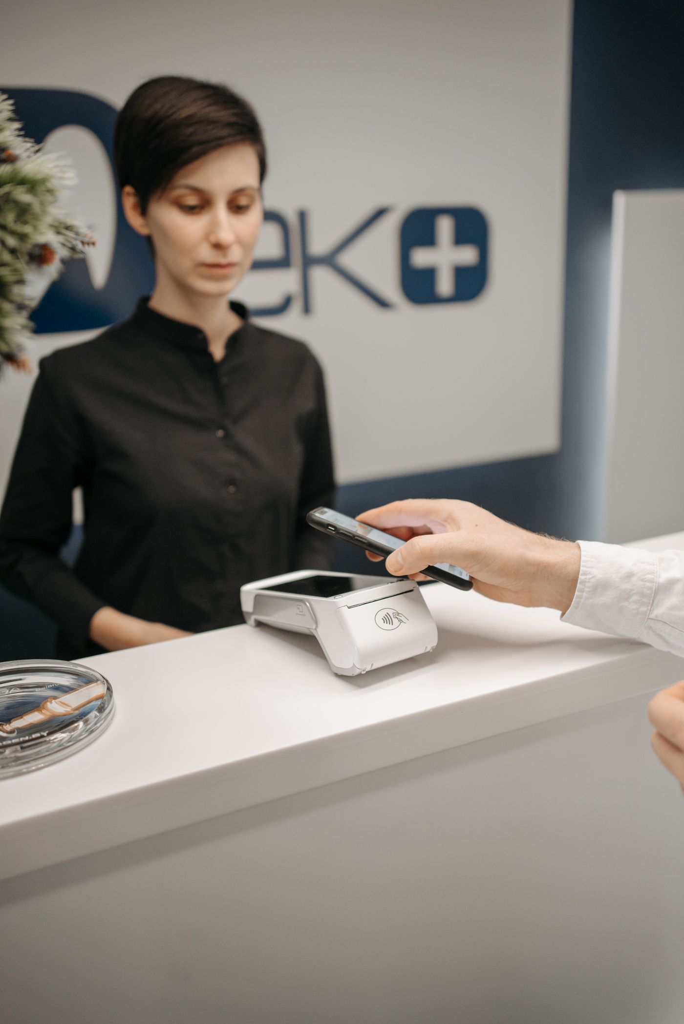 A customer making a smartphone payment at a service counter