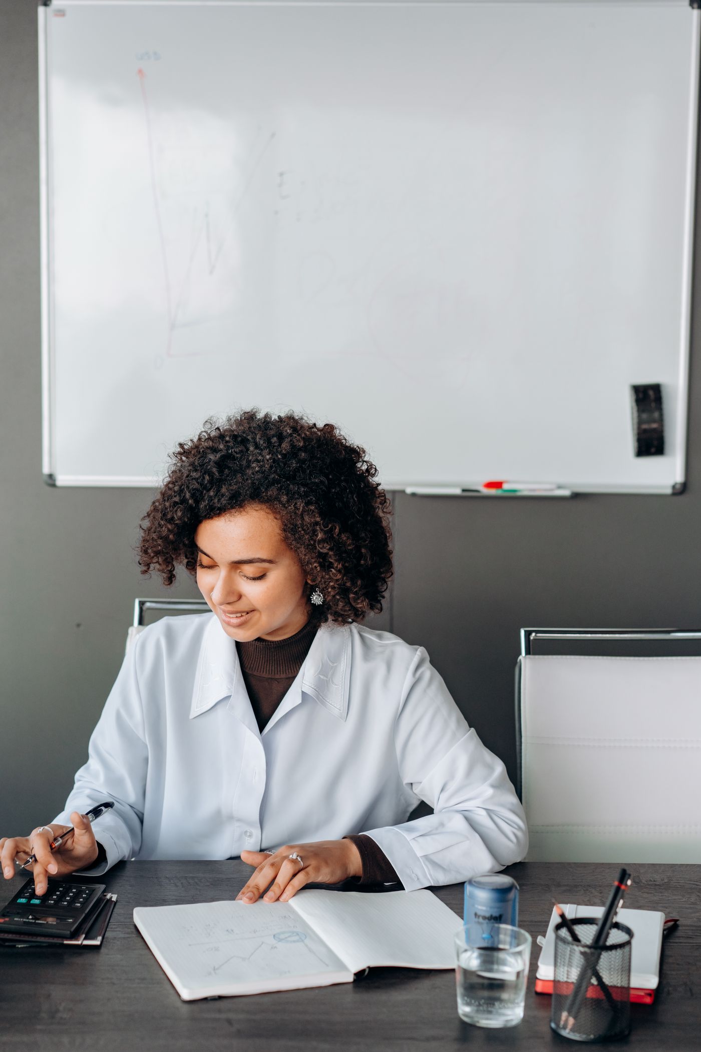 A businesswoman using a calculator beside financial charts